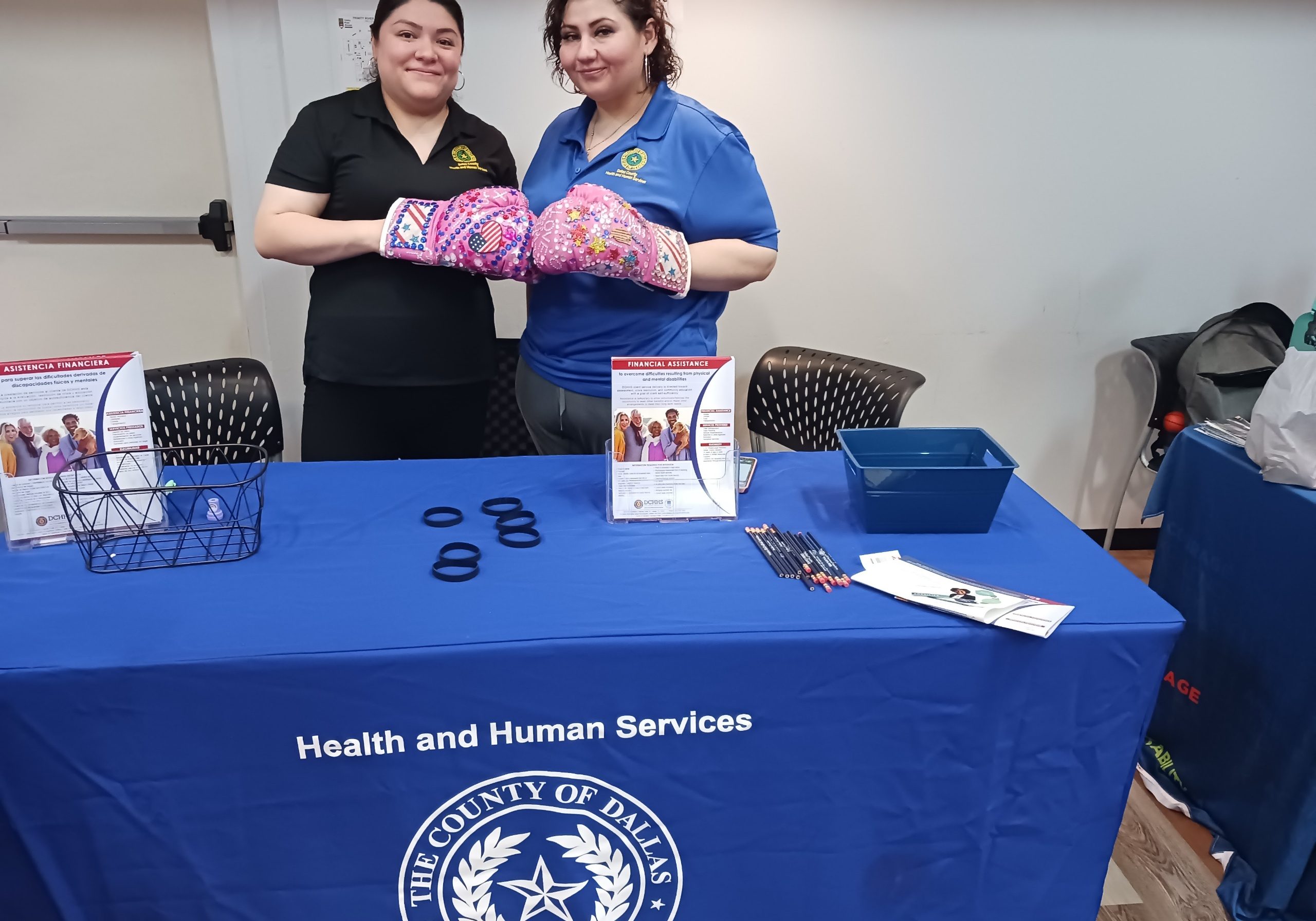 Dallas Country Health and Human Services Table with free swags and two female posing with decorative pink boxing gloves