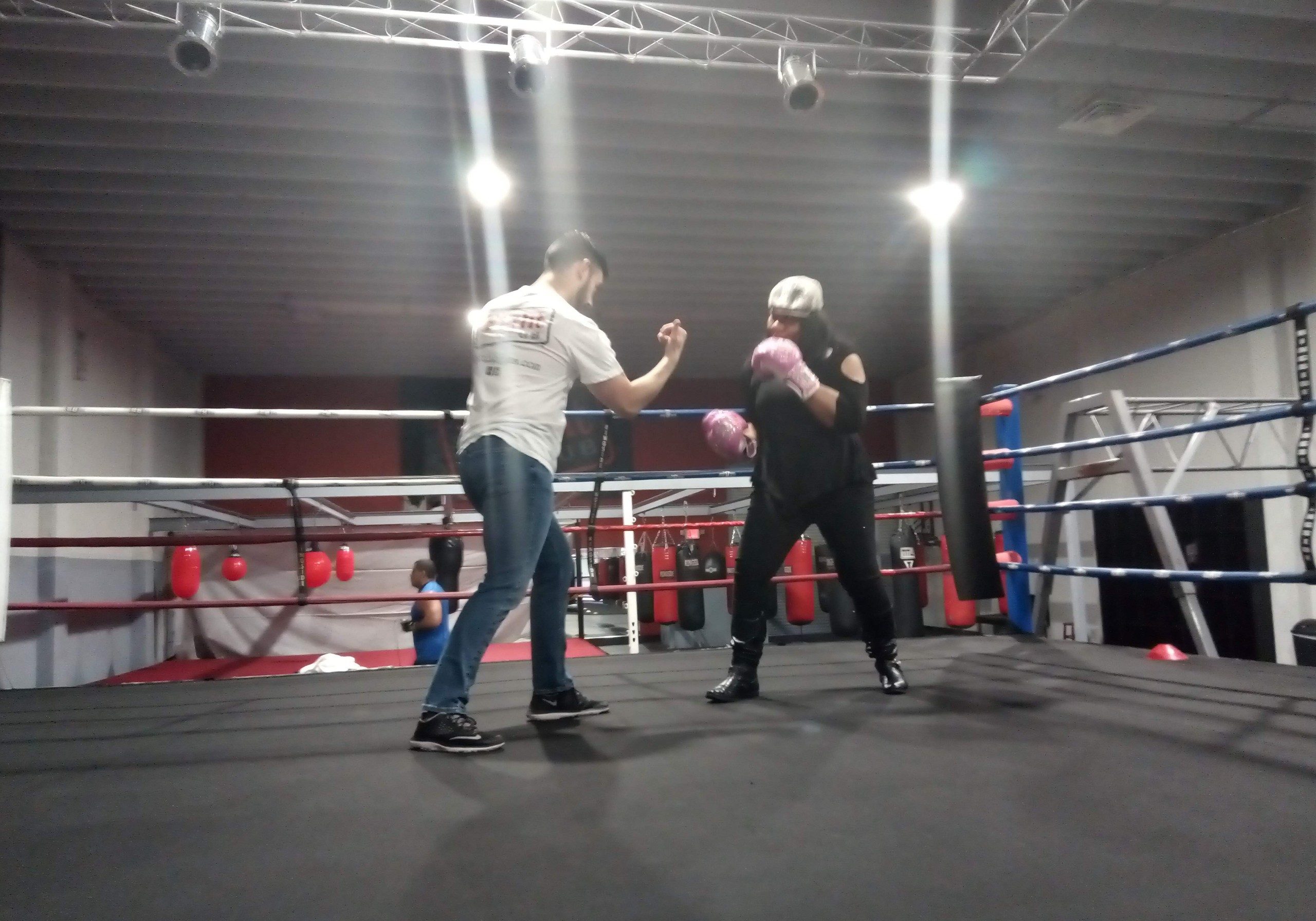 Boxing wearing pink gloves with a coach